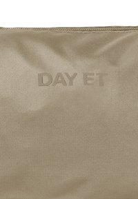 Borsa in nylon beige con logo "DAY ET" in rilievo sulla parte anteriore, caratterizzata da una texture liscia e chiusura con zip in alto.