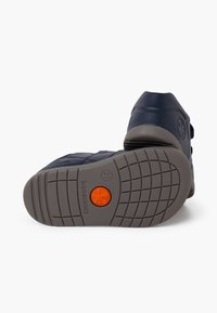 Scarpa blu con suola grigia texturizzata, dettaglio arancione e battistrada decorato. Presenta un design alto con chiusure laterali per una vestibilità sicura.