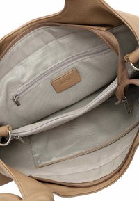 Innenraum einer Handtasche aus hellbraunem Leder mit einem hellbeigen Futter, einer Reißverschlusstasche und glatter Textur mit einem Markenetikett.