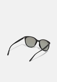 Ochelari de soare negri tip cat-eye cu lentile gri. Rama are un finisaj lucios și brațe subțiri, evidențiind un design minimalist.