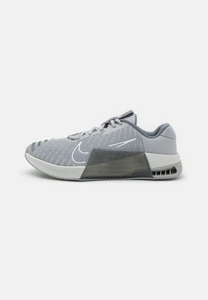 Chaussure de sport gris clair avec empeigne en mesh, semelle blanche, section de talon noire de soutien et logo swoosh blanc sur le côté, vue de profil.