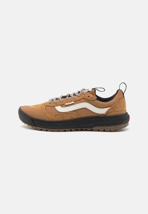Zapatillas de deporte de ante marrón y malla con suela de goma negra, franjas blancas en los laterales y cordones grises, que cuentan con una tira trasera para facilitar su puesta.