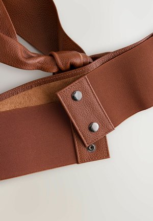 Brun bälte med en texturerad lädersektion, kontrasterande slät tyg och metallknappar för stängning. Snurrad tygdetalj ingår.