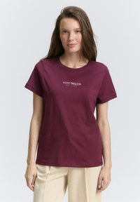 T-shirt en coton bordeaux à manches courtes et col rond, avec un logo "TOM TAILOR" blanc au centre.