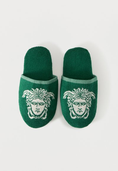 Ζευγάρι πράσινα παντοφλάκια από περκάλι με λευκά σχέδια κεφαλής Μέδουσας στην κορυφή, τοποθετημένα δίπλα το ένα στο άλλο σε άσπρο φόντο.