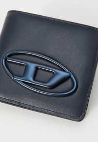 Navy leather wallet with a raised blue emblem. Features a smooth texture, rectangular shape, and tonal stitching along the edges.