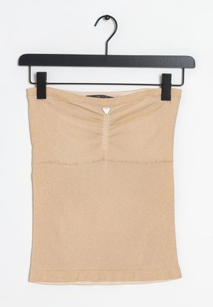 Beige strapless gebreide tube top met geplooide voorkant en klein driehoekig metalen logo, hangend aan een zwarte klemhanger tegen een witte achtergrond.