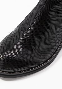 Czarne botki w wężowy wzór z teksturowaną powierzchnią, spiczastym noskiem i cienkim szwem wzdłuż podeszwy. Gładkie wykończenie, elegancki design.