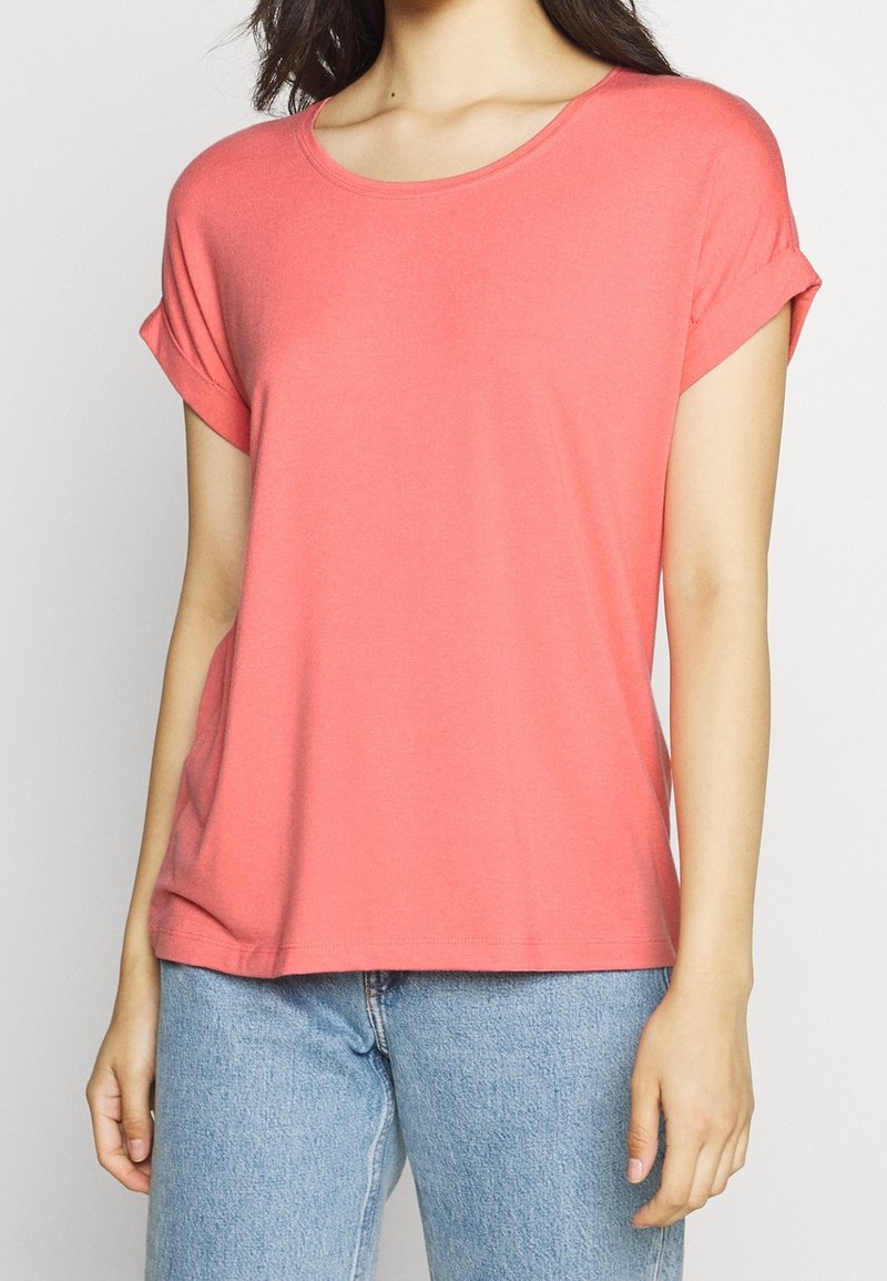 Korallfärgad t-shirt med korta ärmar i mjukt tyg, med rundad halsringning och vända ärmar, kombinerad med ljusblå jeans.