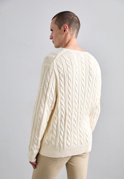 Cream cable-knit sweater with a ribbed hem and cuffs. Features a wide neckline and textured pattern, shown from the back.