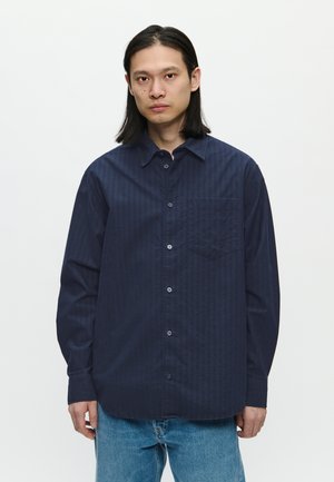 Dark blue, button-up shirt with vertical stripes, long sleeves, and a chest pocket. Fabric appears smooth with subtle texture.