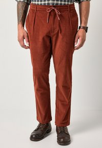 Harmaat corduroy-housut rentoa mallia, joissa on naru vyötäröllä ja laskokset edessä. Yhdistetty tummanruskeisiin nauhakengiin.