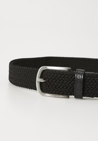 Cinto preto trançado com uma fivela de metal prateado. Apresenta um padrão texturizado e um detalhe em couro com marcação em relevo.