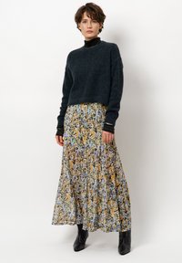 Un pull court en navy foncé au toucher doux, associé �à une jupe longue et fluide avec un motif floral dans des tons jaunes, bleus et bruns. Bottines noires.