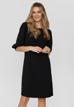Schwarzes Kleid aus strukturiertem Stoff mit 3/4-Ärmeln, lockerer Passform, Rundhalsausschnitt und knieumspielendem Saum. Besitzt ein dezentes Karomuster.