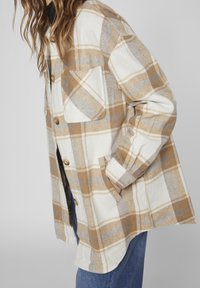 Flanelová košile v kr émovém a béžovém károvaném vzoru, s knoflíkovým zapínáním a kapsou na hrudi. Měkká, texturovaná látka s dlouhými rukávy.