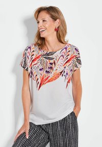 Korte mouwen top in het wit met een kleurrijk veerpatroon in oranje, paars en zwart. Gladde textuur met een ronde halslijn.