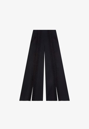 Zwarte wijde broek met verfijnde borduursels langs de zijkanten en een gladde textuur. Twee zakken zijn in het ontwerp geïntegreerd.