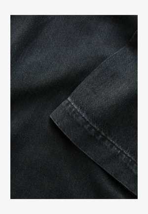 Fekete farmeranyag sima felszínnel, hajtott élekkel és látható varrással, hangsúlyozva masszív kialakítását.