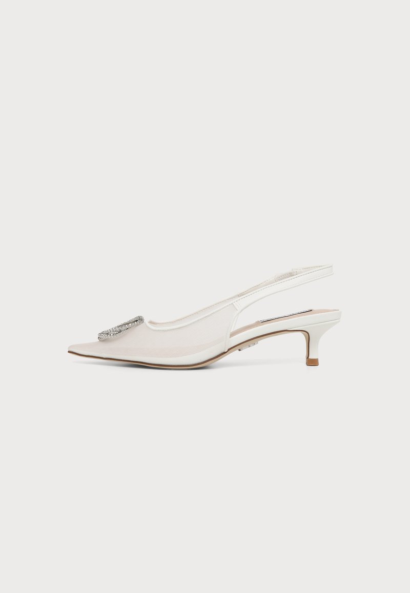 Chaussure blanche pointue à talon kitten avec bride arrière, boucle décorative en strass sur le bout et petit talon sur fond uni.