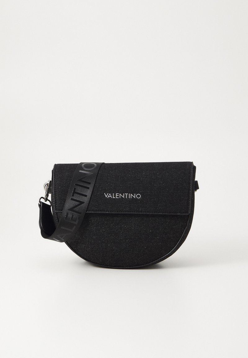 Čierna denimová crossbody taška s guľatým tvarom, ktorá má plochý klapkový uzáver a nastaviteľný popruh s vytlačeným logom "Valentino".