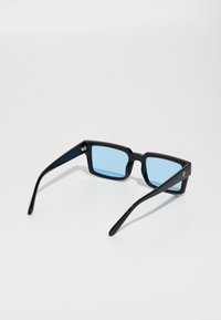 Ochelari de soare negri, dreptunghiulari, cu lentile albastre, având un cadru din plastic lucios și brațe subțiri. Detaliu notabil cu logo pe lateral.