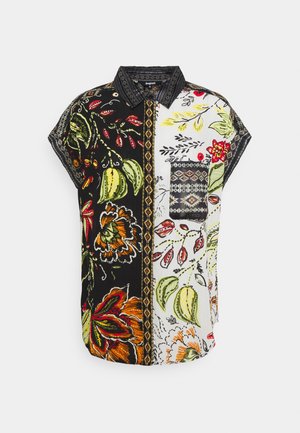 Chemise à manches courtes avec boutons, présentant un design patchwork avec des motifs floraux en vert, orange et noir sur fond blanc.