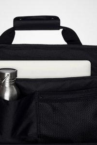 Svart stoffveske med glidelås, utstyrt med et topplokk, en hvit laptop og en sølvfarget vannflaske i lommen. Inkluderer en detalj med nettinglomme.