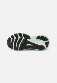 Semelle d'une chaussure de course présentant une surface en caoutchouc noir avec des motifs nervurés et une semelle intermédiaire vert menthe pour un amorti et un soutien.