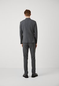 Gray tailored suit with a structured jacket and matching trousers, featuring a smooth texture and classic fit, complemented by black shoes.
