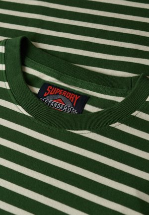 Camiseta a rayas verdes y blancas con cuello redondo acanalado. Presenta una etiqueta tejida con acentos en rojo y azul. Material de algodón.