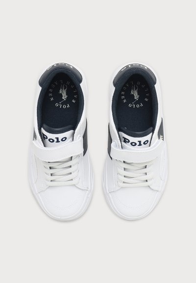 Ζευγάρι λευκά αθλητικά παπούτσια Polo Ralph Lauren με λεπτομέρειες σε ναυτικό μπλε, κορδόνια και λουριά με βέλκρο, εμφανίζεται από πάνω σε ανοιχτό φόντο.
