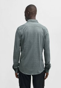 Grijze longsleeve shirt met een gestructureerde stof, opstaande kraag en ronde zoom; heeft knoopmanchetten en een eenvoudig ontwerp.
