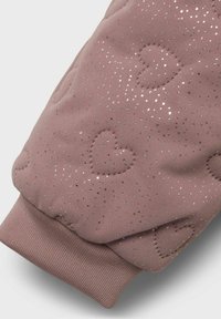 Tessuto imbottito rosa con delicati motivi a cuore e accenti di glitter dorato. Orlo a polsino con una finitura testurizzata. Design morbido e caldo.