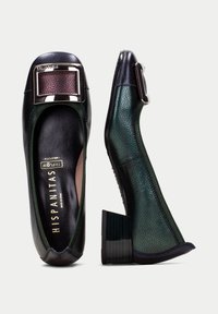 Gröna och svarta läderskor med en texturerad yta. Fyrkantig, metallisk spänne på framsidan. Låg, kloblocktådesign.