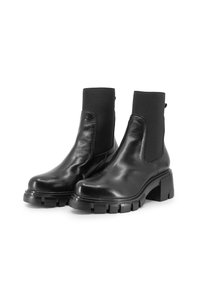 Stivaletti neri in pelle con suola in gomma spessa e pannelli laterali elastici. Presentano una consistenza liscia e una linguetta sul retro.