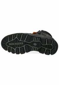 Suela de bota de goma negra con surcos profundos, con el logotipo "DOCKERS" en blanco. El costado tiene una cremallera y un acento naranja. Material y diseño duraderos.