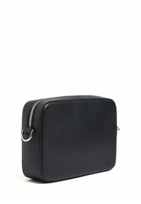 Borsa rettangolare in pelle nera con superficie texturizzata, zip argentata e accessori metallici circolari. Bordo liscio e design minimale.