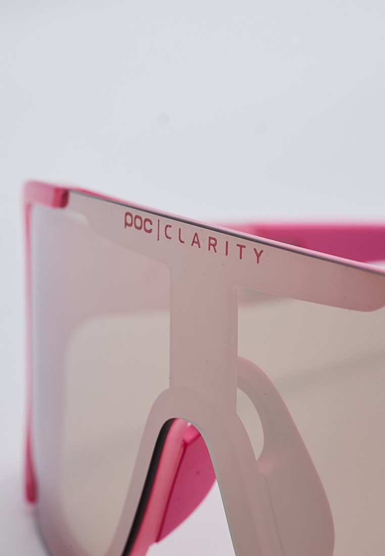 Różowe sportowe okulary przeciwsłoneczne z dużą soczewką, z półprzezroczystą oprawą i teksturowanymi akcentami. Widoczna nazwa marki "poc|CLARITY".