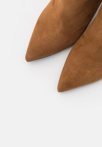 Bruine suède pumps met puntige neus en een gladde textuur, met een strak ontwerp en minimalistische esthetiek. Zwarte, antislipzolen.