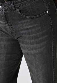 Donkergrijze denim jeans met een lichte glans, met een klassieke vijf-pocket ontwerp, metalen knoopsluiting en subtiele vervaging.