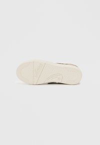 Schwarze Sneaker-Sohle mit strukturiertem weißen Gummi. Markennamen geprägt, entworfen für Grip und Haltbarkeit.