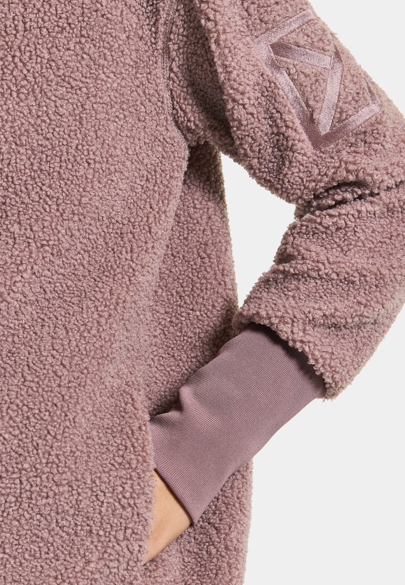 Fleece-Pullover in hellen Mauve mit strukturierter Oberfläche, ausgestattet mit dehnbaren Bündchen und einem Logodetail am Ärmel.