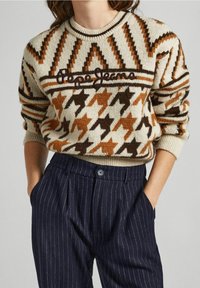 Pull en mélange de laine présentant un motif pied-de-poule beige, marron et orange, avec un col côtelé et un logo brodé.
