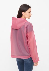 Giacca leggera da pioggia trasparente di colore rosa, con cappuccio, maniche lunghe e polsini con bottone. Texture liscia con vestibilità rilassata.