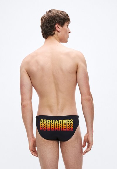 Cuecas de banho pretas com um logótipo de texto em degradê nas cores amarelo e vermelho, textura suave e ajuste justo. Design minimalista com marcação ousada.