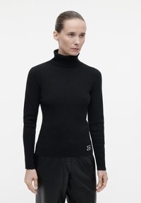 Schwarzer Rollkragenpullover in taillierter Passform, aus weichem Material, mit langen Ärmeln und einem gestickten Logo am Saum.