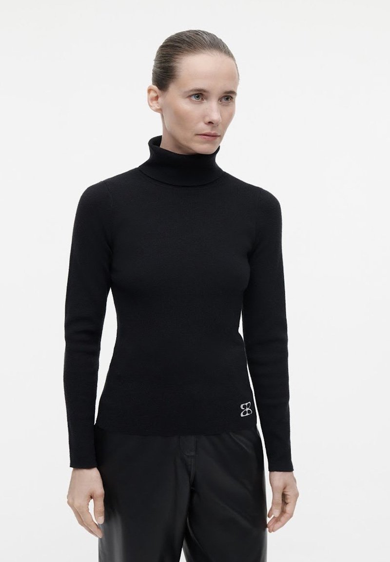 Schwarzer Rollkragenpullover in taillierter Passform, aus weichem Material, mit langen Ärmeln und einem gestickten Logo am Saum.