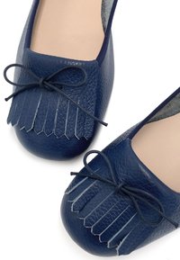 Des ballerines en cuir bleu marine présentent un bout carré avec des détails frangés et un nœud noué, rehaussées d'une doublure douce pour le confort.