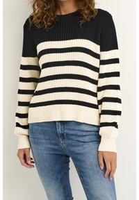 Bomullströja med svarta och gräddvita horisontella ränder, ribbat mönster, rund halsringning och långa ärmar med passande mudd.